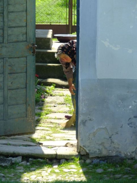 An old women sweeping her side walk in the village